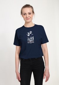 Mørkeblå bomulds t-shirt med et grafisk print af to maskerede figurer og teksten "HELLRAISER". Korte ærmer, afslappet pasform, glat tekstur.