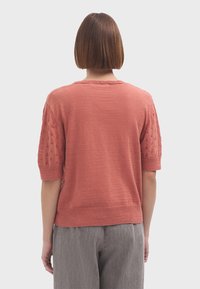 Kortärmad, korallfärgad tröja med texturerad stickning på ärmarna, ribbad nederkant och avslappnad passform. Lättstickad material.