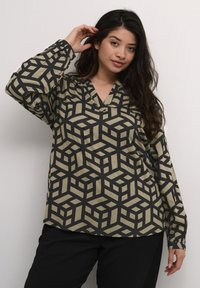 Langärmlige Bluse mit einem geometrischen Muster aus schwarzen und beigen Würfeln, V-Ausschnitt und Knopfdetails an den Manschetten.