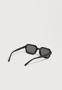 Μαύρα οκταγωνικά γυαλιά ηλίου με σκουρόχρωμους φακούς. Το πλαστικό σκελετό έχει ομαλή υφή και λεπτά μπράτσα. Σημαντική σήμανση στο εσωτερικό του μπράτσου.