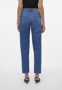 Blugi din denim albastru cu talie înaltă și croială dreaptă, dotati cu două buzunare pe spate și o aplicație din piele pe talie.