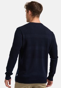 Sötétkék pulóver, vízszintes textúrázott csíkokkal, hosszú ujjal, kerek nyakkal és bordázott mandzsettával. Puha kötött anyagból készült.