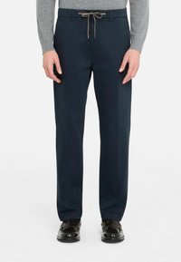 Pantalon en coton bleu marine avec une taille à cordon, coupe droite et une légère brillance, assorti à des chaussures noires.