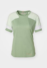 Vihreä urheilupaita, jossa on lyhyet käännetyt hihat, teksturoitu kuvio, kevyen vihreän ja valkoisen väriset väriblokkikorostukset sekä pieni logo.