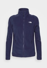 Marineblaue Fleecejacke mit hohem Kragen, durchgehendem Reißverschluss, zwei seitlichen Reißverschlusstaschen und einem kleinen Logo auf der linken Brust. Weiche Textur.