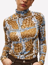 Langärmliges Rollkragenoberteil aus elastischem Stoff. Besitzt ein Muster in Braun, Blau und Weiß mit floralen und tierischen Druckmotiven.