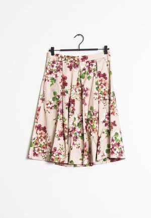 Falda plisada beige con estampado floral rosa, blanco y verde colgada en una percha negra contra un fondo blanco.