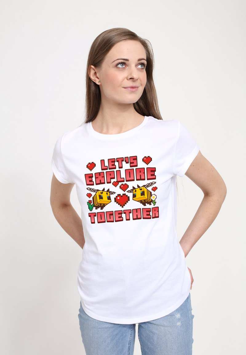 Camiseta blanca de algodón con un diseño colorido de arte en píxeles que incluye el texto "EXPLORAMOS JUNTOS" y dibujos de caricaturas de abejas, corazones y cactus.