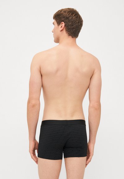 Black boxer briefs made from stretch fabric, featuring a textured pattern with repeated branding, a solid black waistband, and a fitted cut.