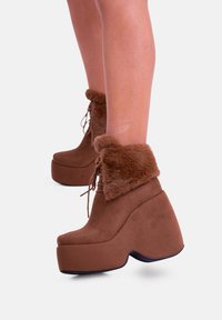Stivali platform marroni con risvolto in pelliccia sintetica, design con lacci, materiale in morbida suede e tacco a zeppa spesso.