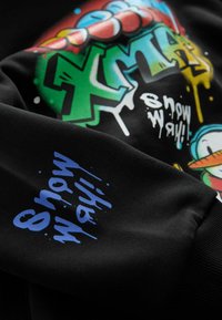Schwarzer Kapuzenpulli mit buntem Graffiti-Stil Text und Grafiken, einschließlich einer Grafik eines Schneemanns, mit blauen Akzenten an den Ärmeln.