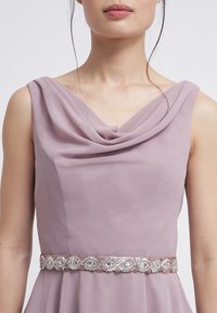 Fialové šaty s drapovaným výstřihem a zdobeným páskem v pase s jemnými stříbrnými a růžovými detaily. Měkká, texturovaná tkanina.