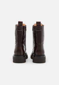 Brown leather ankle boots with a smooth finish, featuring a full-height zipper and elastic side panels for ease of wear. Chunky soles.