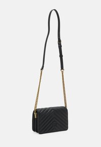 Borsa a tracolla in pelle nera trapuntata con tracolla in catena dorata e dettagli con zip. Presenta un motivo a chevron e un logo stampato sul davanti.