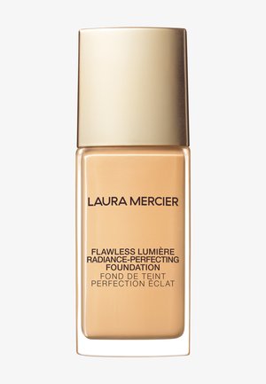 Foundationflaske med firkantet glassbunn og lokk i gullmetall. Merket viser "Flawless Lumière Radiance-Perfecting Foundation" med svart tekst.