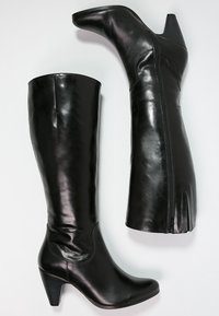 Bottes noires en cuir hautes jusqu'au genou avec un bout pointu, un talon modéré, une texture lisse et un détail de fermeture éclair sur le côté.
