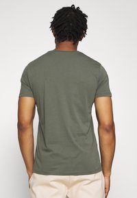 Olivgrünes T-Shirt mit kurzen Ärmeln, von hinten gezeigt, mit einem einfachen Rundhalsausschnitt und einer glatten, baumwollähnlichen Textur.