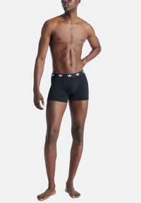 Svarta boxertrosor med en åtsittande design, med en deformerbar midja med vitt logo. Tillverkade av mjukt tyg med en slät textur.