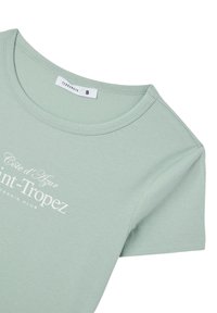 T-shirt verde chiaro a maniche corte con scollo tondo e testo bianco: "Côte d'Azur Saint-Tropez Tennis Club." Realizzato in tessuto morbido.