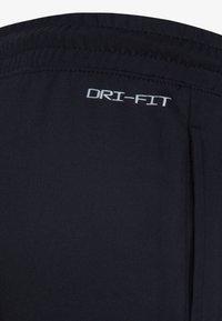 Crne atletske kratke hlače izrađene od tkanine koja upija vlagu. Imaju "DRI-FIT" logo u bijeloj boji, elastičan pojas i bočne džepove.