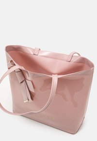 Borsa a spalla rosa lucida con texture liscia, dotata di due manici e un dettaglio a fiocco decorativo. L'interno è di un colore rosa abbinato. Logo dorato sulla parte anteriore.