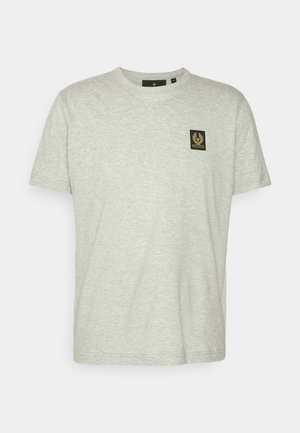 Maglietta a maniche corte grigio chiaro, realizzata in un tessuto morbido, presenta una piccola toppa quadrata nera con un emblema dorato sul lato sinistro del petto.