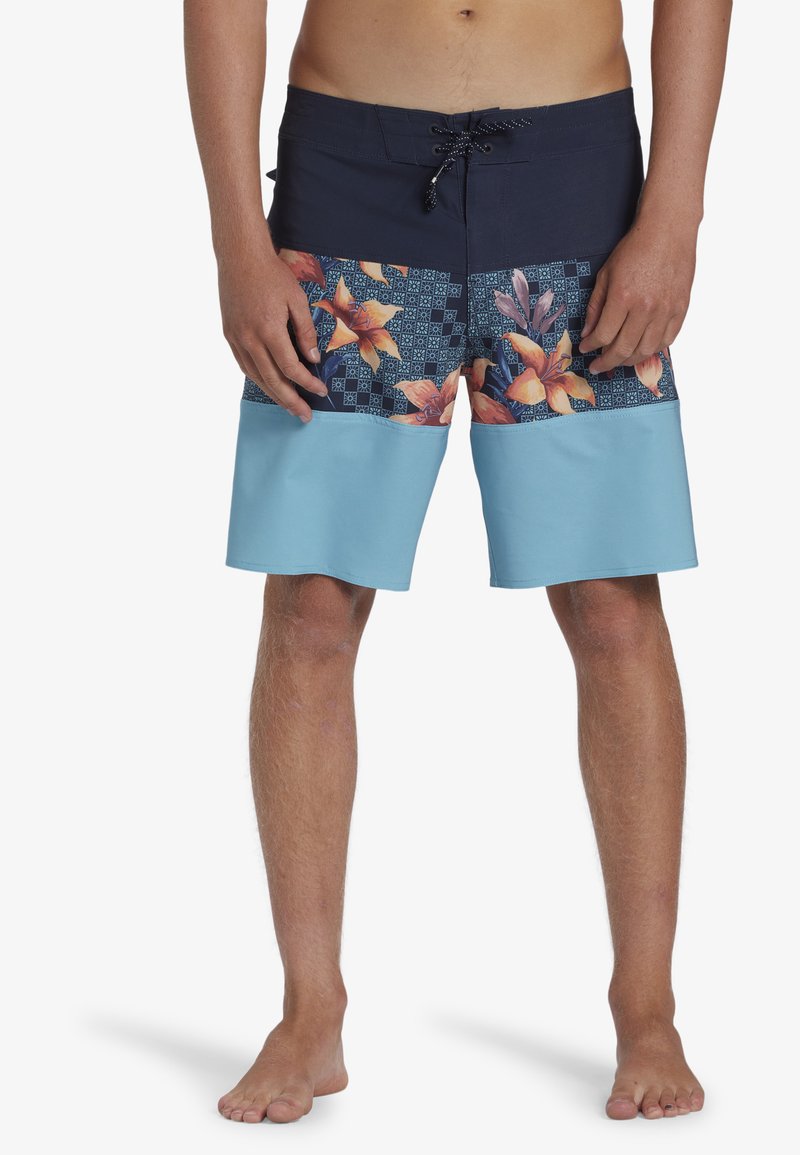 Shorts de bain pour homme avec un motif floral en bleu et marine, présentant une section inférieure unie en bleu clair, une taille élastique et un cordon de serrage.