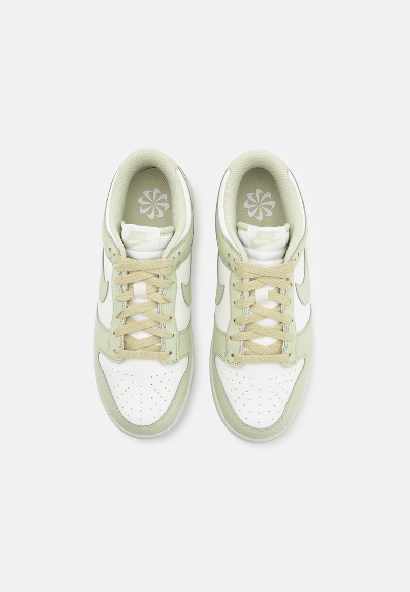 Nike-sneakers met een bovenwerk van wit leer, lichtgroene accenten, beige veters en een geperforeerde neus. Heeft een bloemenlogo op de inlegzool.