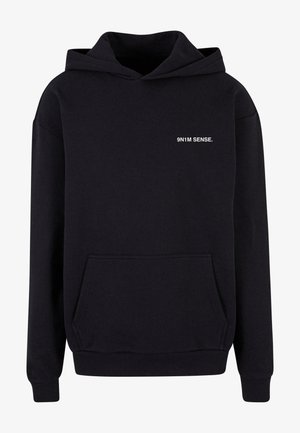 Zwarte hoodie van een katoenmix, met een voorzak en ribbelmanchetten. Witte tekst "9N1M SENSE." gedrukt op de borst.