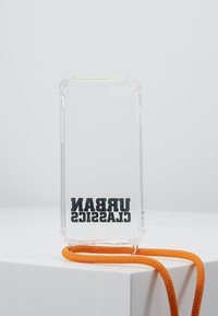 Clear phone case with rounded edges, featuring bold black text "URBAN CLASSICS" at the bottom and an orange braided strap attached.