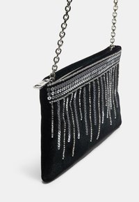 Sortvelvet clutch taske med pailletkantdesign, sølvfarvet kædestropp og lynlås lukning på toppen. Skinnende pailletter skaber et tekstureret mønster.