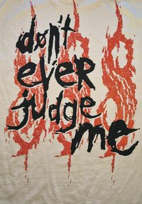 Biała koszulka z wyraźnym czarnym i czerwonym napisem „nie oceniaj mnie nigdy”, z teksturą w stylu pociągnięć pędzla.