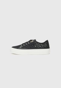 Svart sneakers med vevd stoffdetalj og glatte aksenter. Har en hvit plattformsåle, snøring foran og gulløyelsetilbehør.