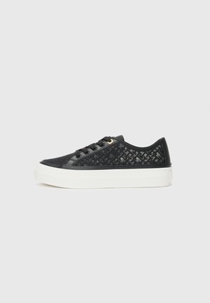 Sneaker noir avec des détails en tissu tissé et des accents lisses. Présente une semelle plateforme blanche, un avant lacé et des embellissements en œillets dorés.