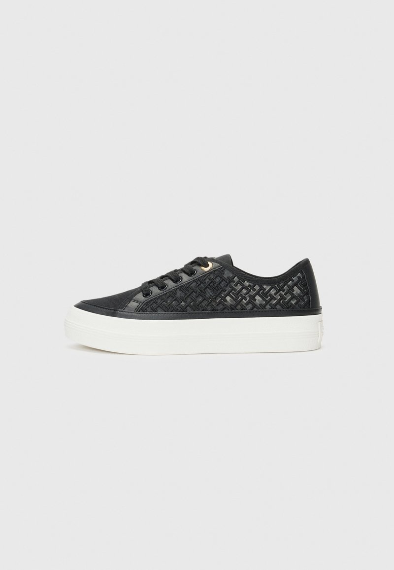 Svart sneakers med vevd stoffdetalj og glatte aksenter. Har en hvit plattformsåle, snøring foran og gulløyelsetilbehør.