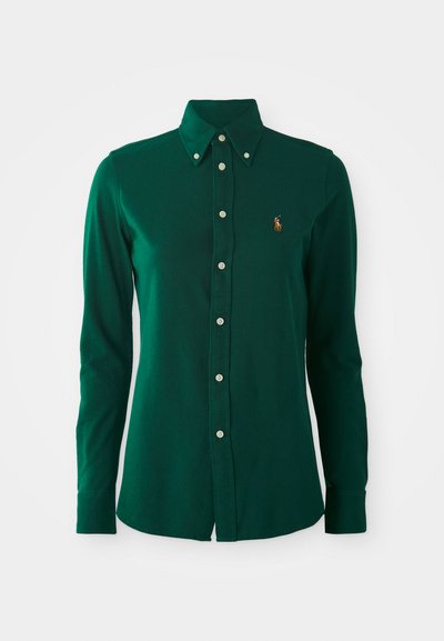 Green long-sleeve collared shirt made of cotton. Features a button front, silver buttons, and a small embroidered logo on the upper left side.