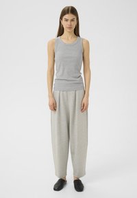 Hallukas halli ribaga särk koos laia jala hallide pükstega. Sile tekstuur ja keha lähedane siluett. Mustad libisemisega kingad täiendavad rõivastust.