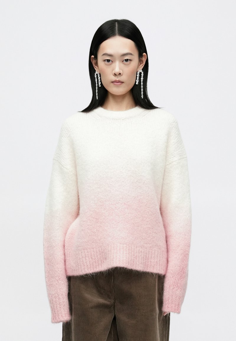 Ombre strikket sweater, der går fra hvid til lyserosa, med rund hals og lange ærmer. Blødt, tekstureret stof.
