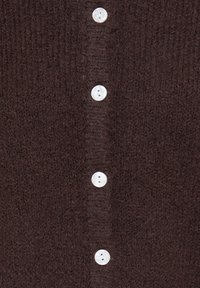 Tissu tricoté marron foncé avec une rangée verticale de quatre boutons ronds blancs espacés uniformément au centre.