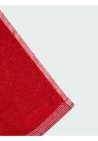 Tela roja texturizada con un borde a cuadros en rojo y blanco, que muestra un diseño tejido y un ángulo diagonal.