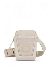 Beige axelremsväska i nylon med en strukturerad frontpanel, justerbar rem och en liten märkt lapp framtill.