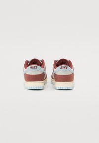 Ténis Nike em malha bordeaux e cinza, com uma sola azul clara, colarinho acolchoado e logótipo no calcanhar. Tecido texturizado e design em camadas.