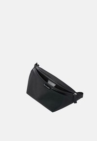 Svart nylonpåse med en böjd design, dragkedjestängning och logotypdetalj. Slät textur och ingen synlig hårdvara. Kompakt storlek.