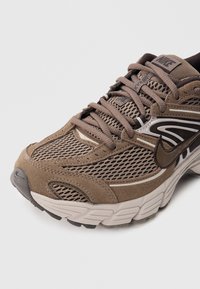 Rudas sportinis batelis su tinklelio viršumi, zomšiniais akcentais ir gumine padu. Turi raištelius ir logotipą ant liežuvio, pabrėžiant sportišką dizainą.