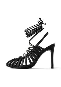 Sandal nera con tacco alto, dal design con cinturini e punta aperta, caratterizzata da bande in pelle verticali e una sottile cinghia alla caviglia. Finitura lucida.