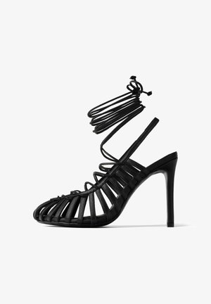 Czarna sandał wysoki na obcasie o paskowym wzorze i otwartym palcu, z pionowymi skórzanymi paskami i cienkim paskiem wokół kostki. Błyszczące wykończenie.