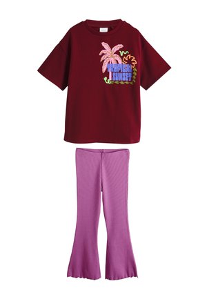 Kortärmlig kastanjebruine T-shirt met een roze palmboom en de tekst "Tropical Sunset", gecombineerd met paars uitlopende broek met hoge taille.
