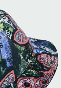 Multi-colored cap featuring a graphic print with red, green, and blue patterns, a curved brim, and textured fabric with visible stitching.