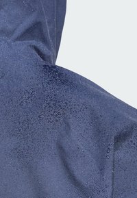 Tela impermeable en color navy con gotas de agua visibles, que muestra una textura suave y una superficie duradera en una chaqueta.
