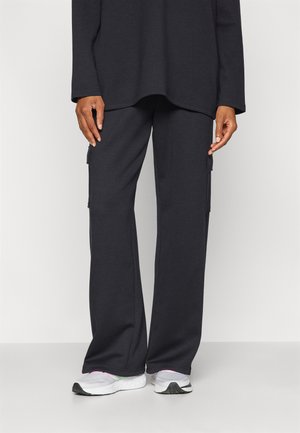 Pantalons cargo gris foncé à coupe décontractée, avec poches latérales et texture douce et lisse. Portés avec des baskets de sport blanches.